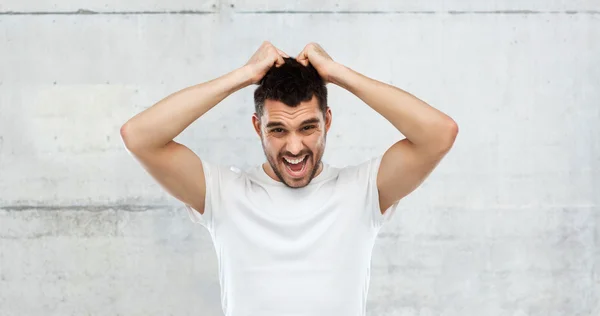 Louco gritando homem em t-shirt sobre fundo cinza — Fotografia de Stock