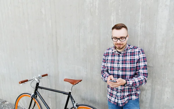 Хипстер человек в наушниках со смартфоном и велосипедом — стоковое фото