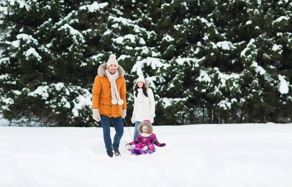 Gelukkige familie met slee wandelen in winter woud — Stockfoto