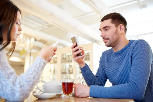 Pareja con teléfonos inteligentes beber té en la cafetería —  Fotos de Stock