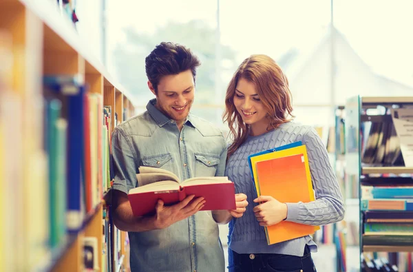 Feliz casal de estudantes com livros na biblioteca — Fotografia de Stock