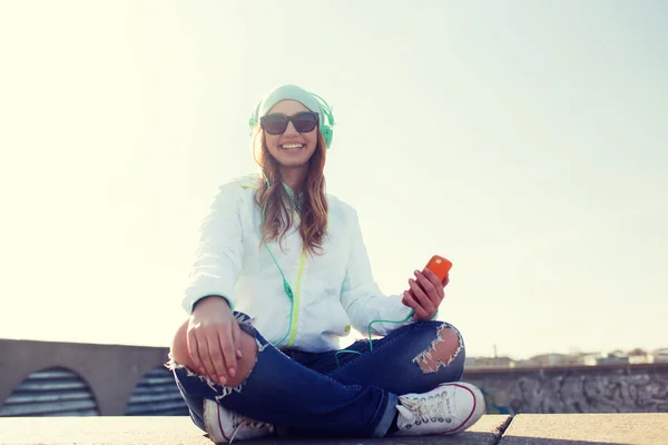 Feliz joven con teléfono inteligente y auriculares — Foto de Stock