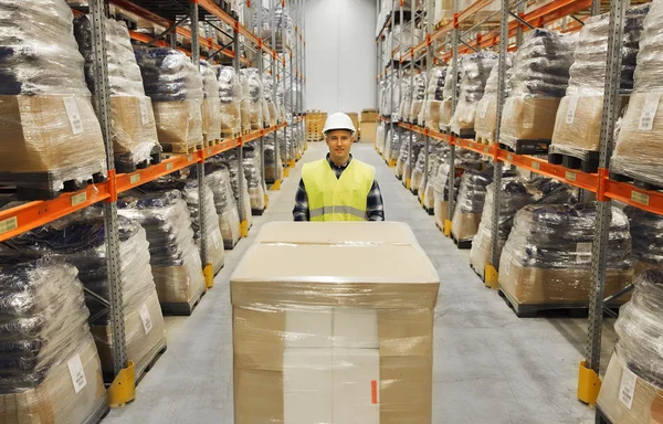 Smiling man in hardhat loading cargo at warehouse — Stock Photo, Image