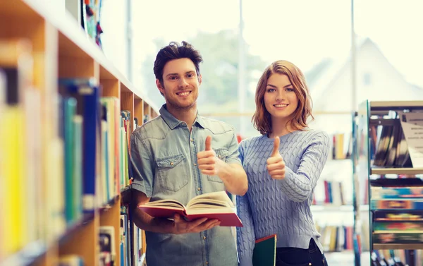Feliz casal de estudantes com livros na biblioteca — Fotografia de Stock