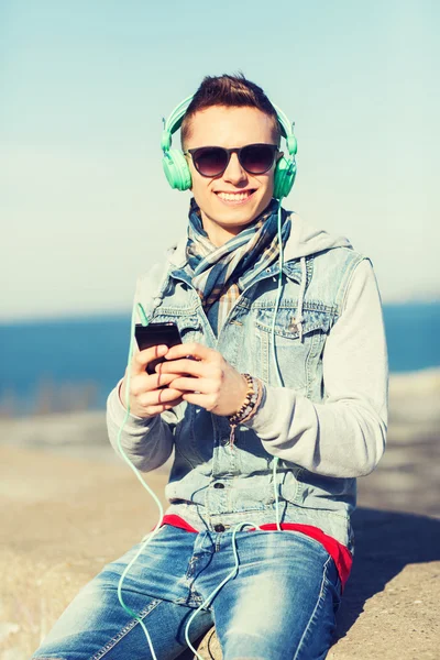 Jeune homme heureux dans les écouteurs avec smartphone — Photo