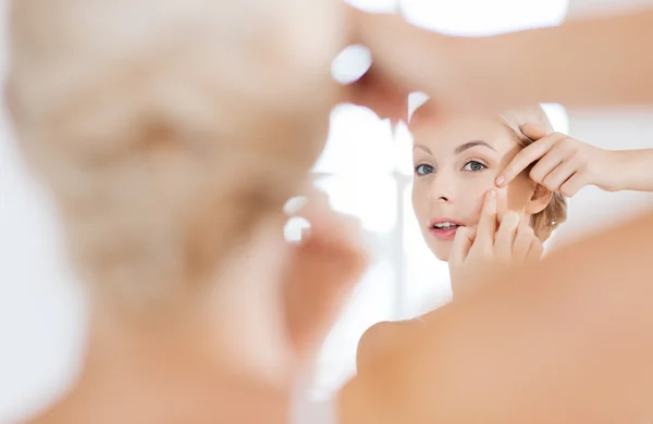 Mujer apretando espinilla en el espejo del baño — Foto de Stock