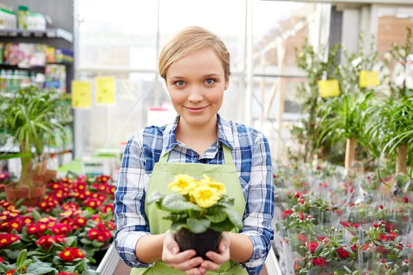 Mujer feliz sosteniendo flores en invernadero o tienda — Foto de Stock