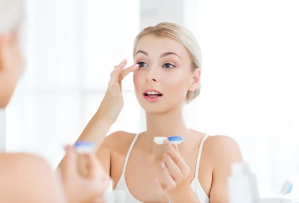 Junge Frau setzt Kontaktlinsen im Badezimmer auf — Stockfoto