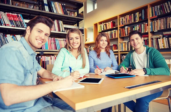 Zufriedene Schüler schreiben in Bibliothek an Notizbücher — Stockfoto