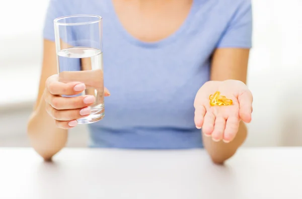 Close up of woman hands with capsules and water — Stock Photo, Image