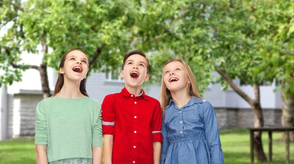 Amazed boy and girls looking up over backyard — Stock Fotó