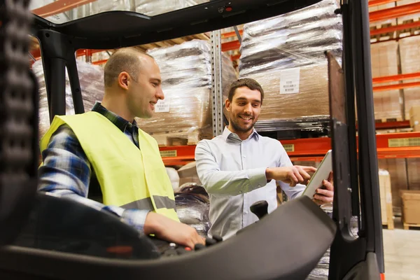 Hombres felices con la tableta PC y la carretilla elevadora en almacén — Foto de Stock