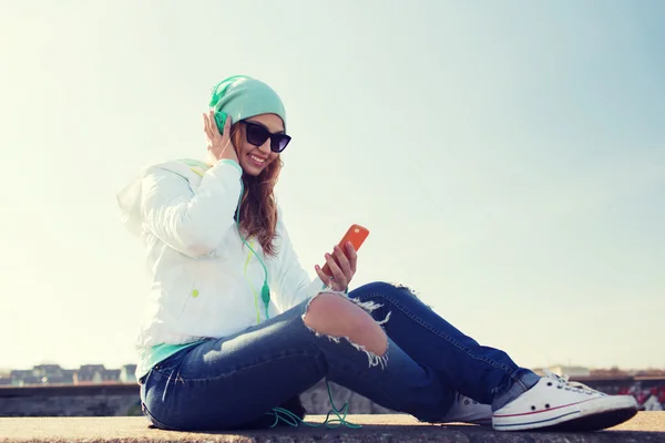 Ευτυχισμένος νεαρή γυναίκα με το smartphone και ακουστικά — Φωτογραφία Αρχείου