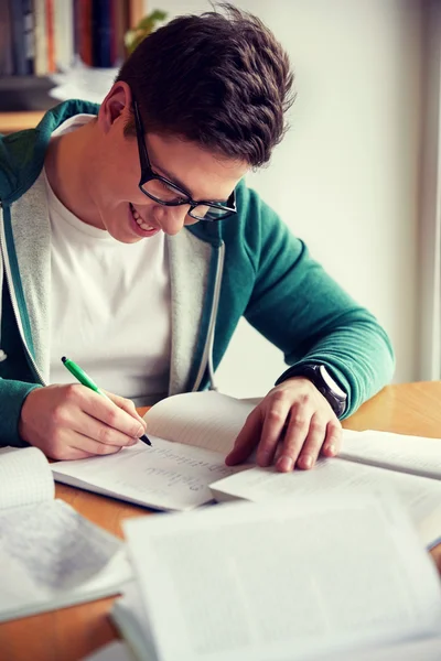 Menino estudante feliz escrevendo para notebook na biblioteca — Fotografia de Stock