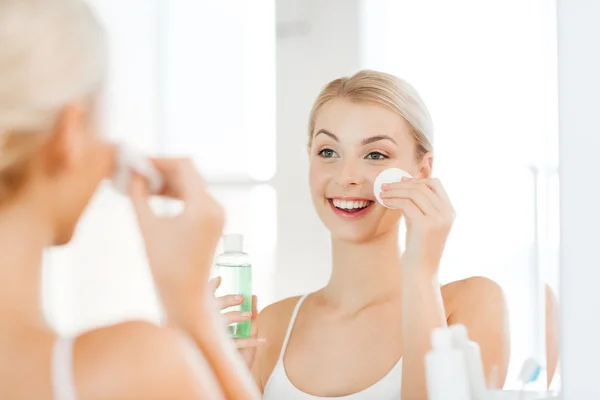 Young woman with lotion washing face at bathroom — Stock Photo, Image