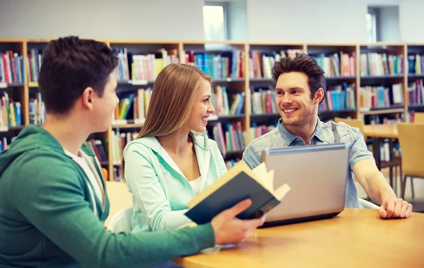 Dizüstü bilgisayar ve Kitap Kütüphanesi'nde mutlu öğrenciler Telifsiz Stok Imajlar