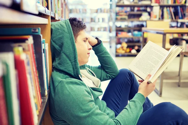 Diák fiú vagy fiatal ember olvasó könyv könyvtár — Stock Fotó