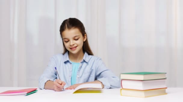 Chica de la escuela feliz con libros y bloc de notas en casa — Vídeos de Stock