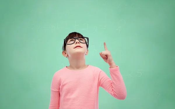 Счастливая маленькая девочка в очках, указывающая пальцем вверх — стоковое фото