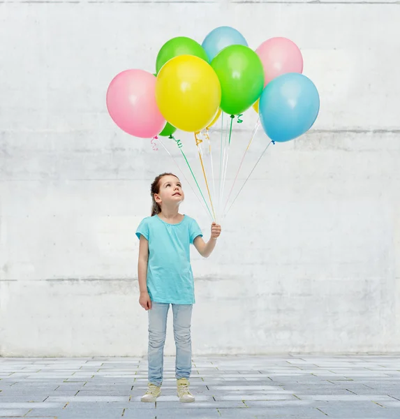 Fille levant les yeux avec un tas de ballons d'hélium — Photo