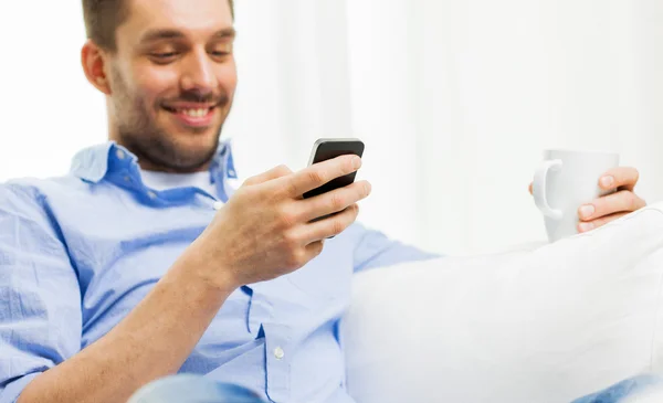 Hombre sonriente mensaje de texto en el teléfono inteligente en casa — Foto de Stock
