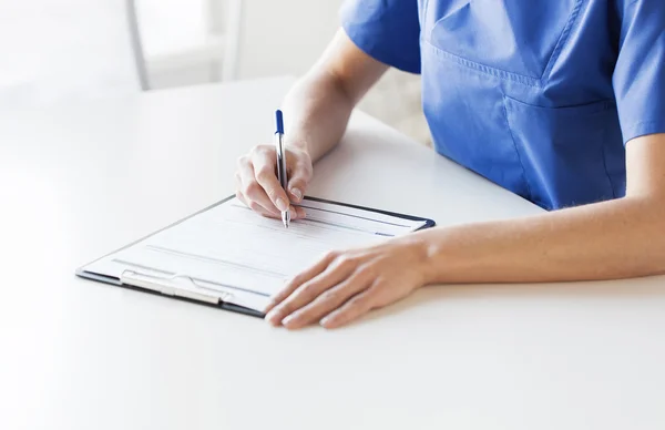 Close-up de médico ou enfermeiro escrevendo para área de transferência — Fotografia de Stock