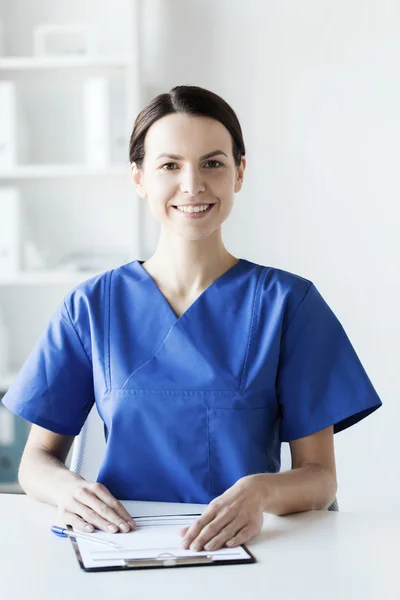Happy doctor or nurse with clipboard at hospital — Stock Photo, Image
