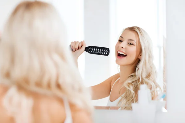 Mulher feliz cantando para escova de cabelo no banheiro — Fotografia de Stock