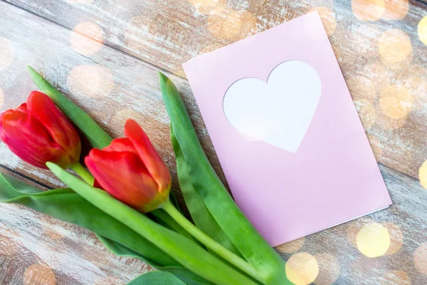 Primer plano de tulipanes y tarjeta de felicitación con corazón — Foto de Stock