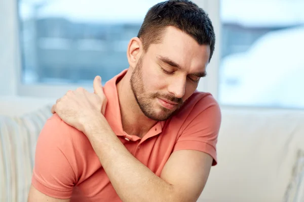 Unhappy man suffering from neck pain at home — Stock Photo, Image