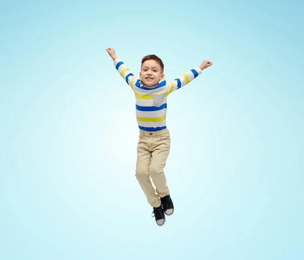 Happy little boy jumping in air over blue — Zdjęcie stockowe