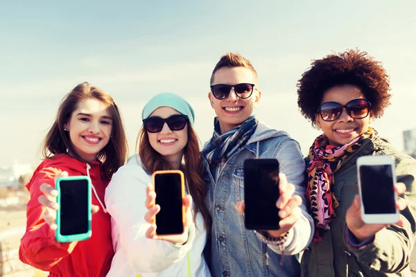 Amici sorridenti che mostrano schermi vuoti dello smartphone — Foto Stock