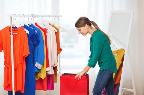 Mujer feliz con bolsas de compras y ropa en casa — Foto de Stock