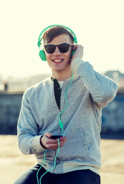 Jeune homme heureux dans les écouteurs avec smartphone — Photo