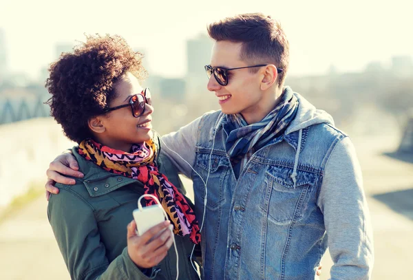 Casal sorridente com smartphone e fones de ouvido — Fotografia de Stock