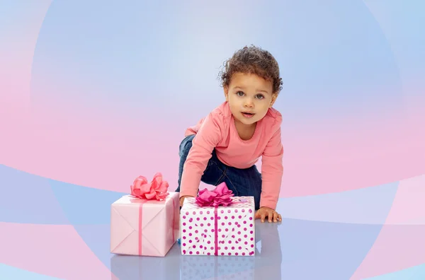 Baby girl with birthday presents and confetti — Stock Photo, Image