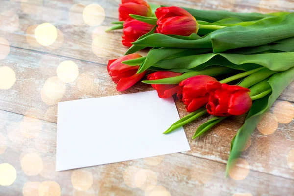 Primer plano de tulipanes rojos y papel o carta en blanco — Foto de Stock