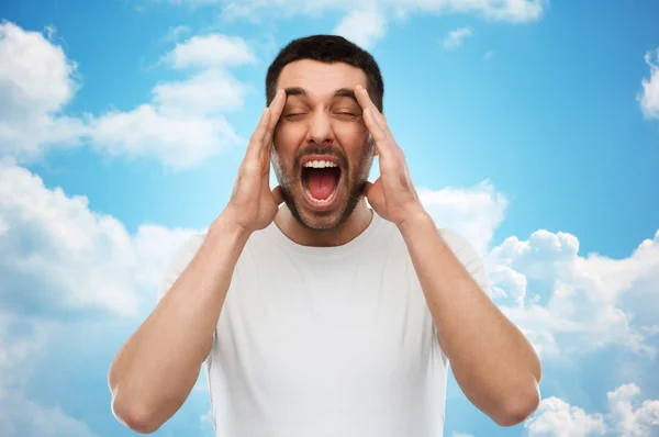 Crazy shouting man in t-shirt over blue sky — 图库照片