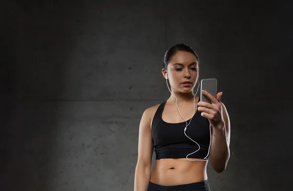 Frau mit Smartphone und Kopfhörer im Fitnessstudio — Stockfoto