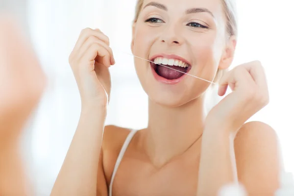 Femme avec fil dentaire nettoyage des dents à la salle de bain — Photo