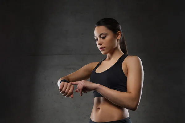 Mujer joven con reloj de ritmo cardíaco en el gimnasio — Foto de Stock