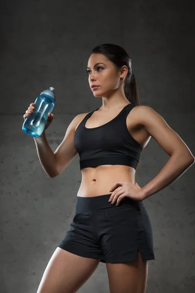 Mujer bebiendo agua de la botella en el gimnasio — Foto de Stock