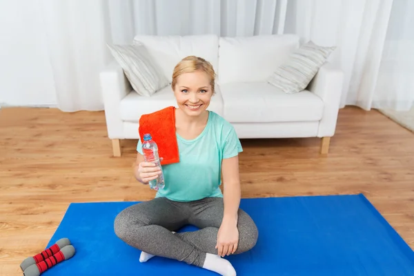 Glückliche Frau trinkt Wasser und trainiert zu Hause — Stockfoto