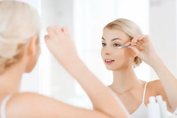 Wanita memperbaiki makeup dengan kapas swab di kamar mandi — Stok Foto