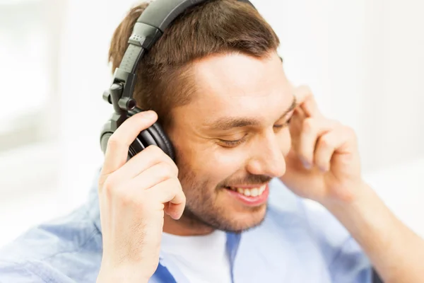 Sorrindo jovem em fones de ouvido em casa — Fotografia de Stock