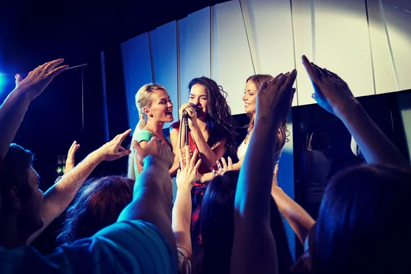 Mujeres jóvenes felices cantando karaoke en el club nocturno —  Fotos de Stock