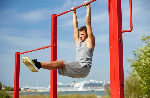 Jovem exercendo na barra horizontal ao ar livre — Fotografia de Stock
