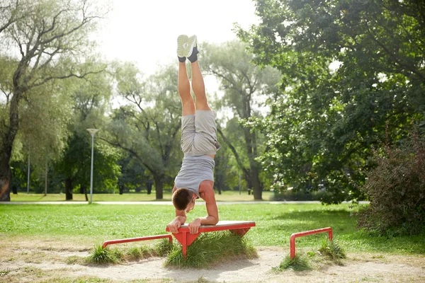 Ung man utövar på bänk på sommaren park — Stockfoto