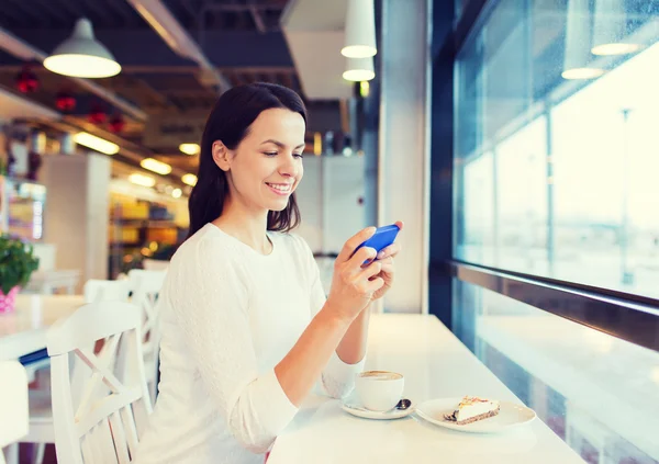 微笑与智能手机和咖啡在咖啡厅的女人 — 图库照片