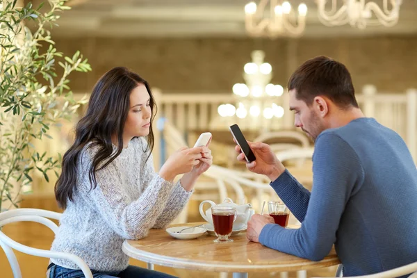 Par med smartphones dricka te på café — Stockfoto